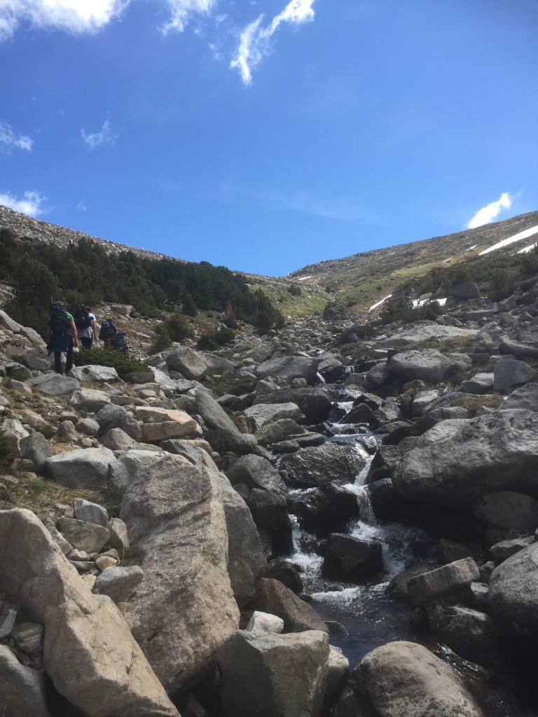 Hikers following a mountain stream up a rocky slope toward Sylvan ridge.